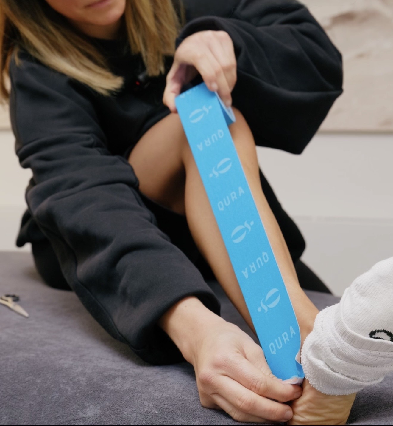 Blaues Kinesio-Tape wird am Unterschenkel angelegt